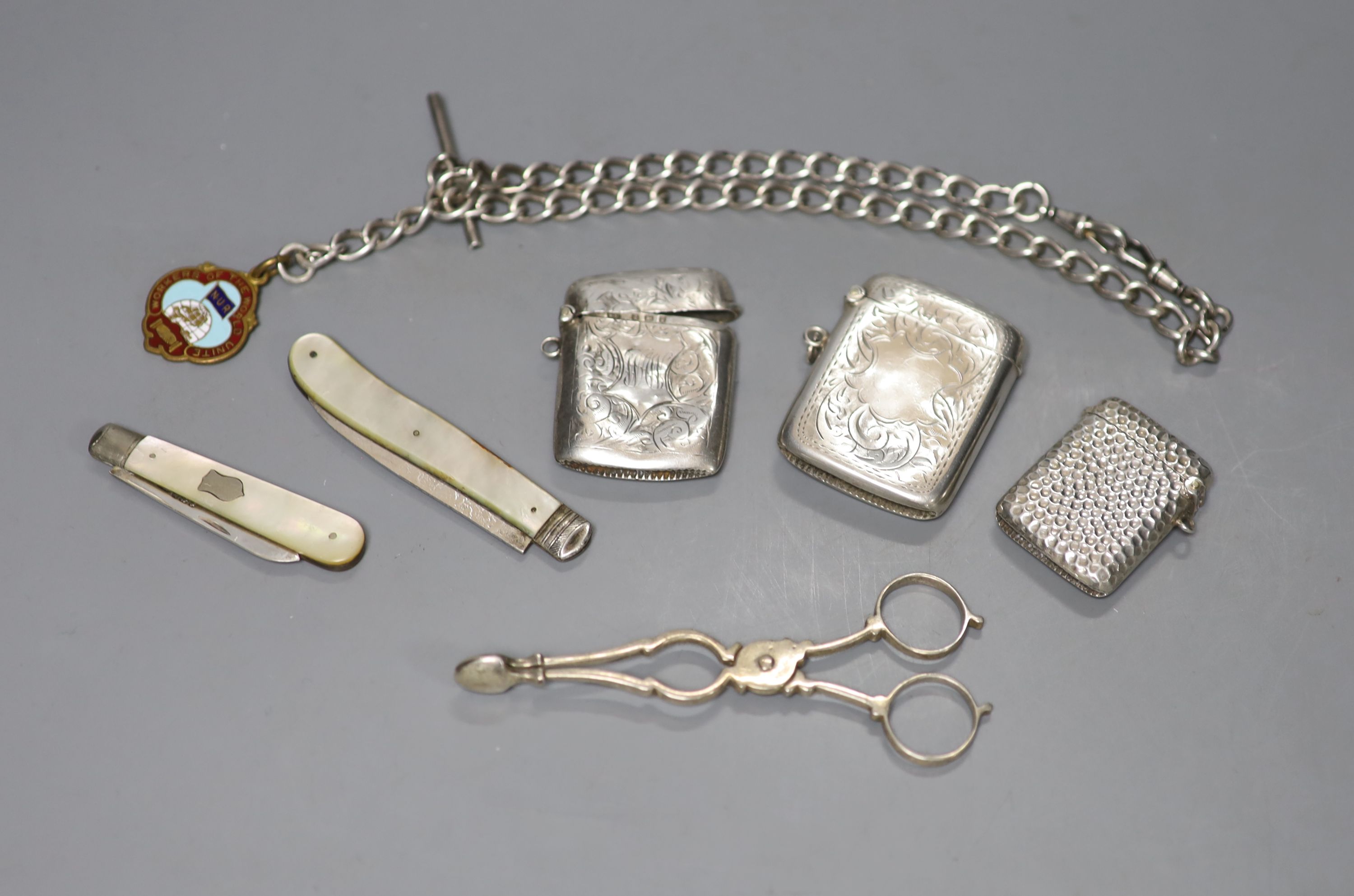 Small silver including a pair of sugar nips, three vesta cases, two fruit knives an albert with gilt medallion.